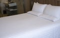 Clean white bed in hotel. White comfortable pillow on bed in bedroom. Bed sheets and pillows. Royalty Free Stock Photo