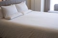 Clean white bed in hotel. White comfortable pillow on bed in bedroom. Bed sheets and pillows. Royalty Free Stock Photo