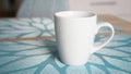 Clean white mug with handle stands on blue table