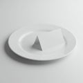 A clean, white plate sits on a flat surface. Centered on the plate is a small, white folde Royalty Free Stock Photo