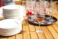 Clean white plates and wine glasses on wooden table in outdoor restaurant on sunny day Royalty Free Stock Photo