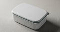 Clean white rectangular plastic lunch box with a subtle teal accent line and smooth rounded edges on a textured Royalty Free Stock Photo