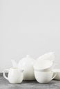 Clean white tableware teapot, cups, saucers on a gray backgrou