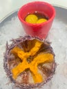 A cleaned sea urchin with a cut shell and caviar inside in the shape of a star lies on the ice, next to a glass with a Royalty Free Stock Photo