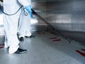 Cleaner employee team use sanitizer spray gun on footprint symbol area with social distancing inside corporate elevator for