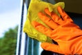 Cleaner in a glove washes a window orange yellow cloth close-up. Royalty Free Stock Photo