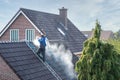 Cleaner with pressure washer at roof house cleaning roof tiles Royalty Free Stock Photo