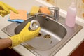 Cleaner in rubber gloves shows clean plughole protector of a kitchen sink