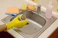 Cleaner in rubber gloves shows waste in the plughole protector of a kitchen sink Royalty Free Stock Photo