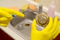 Cleaner in rubber gloves shows waste in the plughole protector of a kitchen sink Royalty Free Stock Photo