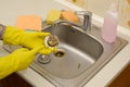 Cleaner in rubber gloves shows waste in the plughole protector of a kitchen sink Royalty Free Stock Photo