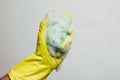Hand in yellow glove with a green sponge for cleaning with foam