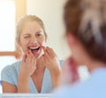 Cleaning all those hard to reach places. a young woman flossing her teeth in a mirror. Royalty Free Stock Photo