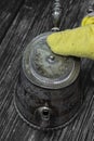 Cleaning antique tarnished silver teapot with a yellow duster.