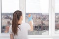 Cleaning of apartments, offices, cottages, warehouses, garages. Young woman washes a window with a cleaning spray