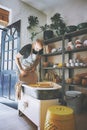 Cleaning as you go is the way to go. a young man cleaning a pottery wheel in a ceramic studio.