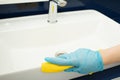 Cleaning the bathroom, a hand with a rag wipes the sink Royalty Free Stock Photo