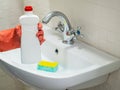 Person hand holding a detergent in white bottle for cleaning bathroom sink Royalty Free Stock Photo