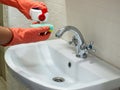 Person hand holding a detergent in white bottle for cleaning bathroom sink Royalty Free Stock Photo