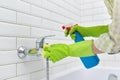 Cleaning the bathroom, woman washing tile wall and mixer with washcloth with detergent