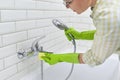 Cleaning the bathroom, woman washing tile wall and mixer with washcloth with detergent