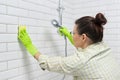 Cleaning the bathroom, woman washing tile wall with washcloth with detergent