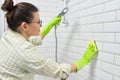 Cleaning the bathroom, woman washing tile wall with washcloth with detergent