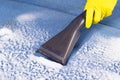 Cleaning a blue upholstered sofa with special foam using a brush on a vacuum cleaner