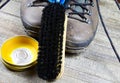 Cleaning brown dirty leather boots: Shoes, box with shoe wax, blue cloth and black brush on wood table Royalty Free Stock Photo