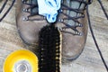 Cleaning brown dirty leather boots: Shoes, box with shoe wax, blue cloth and black brush on wood table Royalty Free Stock Photo