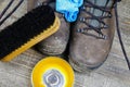Cleaning brown dirty leather boots: Shoes, box with shoe wax, blue cloth and black brush on wood table Royalty Free Stock Photo