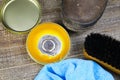 Cleaning brown dirty leather boots: Shoes, box with shoe wax, blue cloth and black brush on wood table Royalty Free Stock Photo