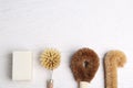 Cleaning brushes and soap bar on white wooden table, flat lay with space for text. Dish washing supplies Royalty Free Stock Photo