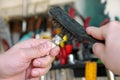 Cleaning a car engine spark plug with wire brush in car garage. Mechanic is brushing used spark plug with a stainless steel brush.