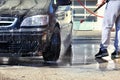 Cleaning Car Using High Pressure Water. Man washing car under high pressure water in service