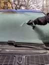 Cleaning car windows in winter. Man scrapes hoarfrost with a plastic scraper from thewindshield of a blue car. Royalty Free Stock Photo