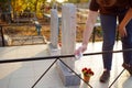 Cleaning cemetery. A woman`s hand washes black fence at grave with rag.