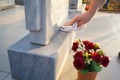 Cleaning cemetery. A woman`s hand washes grey monument at the grave with rag