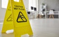 Close up of yellow plastic standing safety sign warning us about wet slippery office floor. Royalty Free Stock Photo