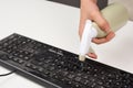 Cleaning computer keyboard in office, spraying water with a spray bottle dusty and dirty electronic, housework Royalty Free Stock Photo