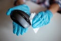 Cleaning a computer mouse device with a disposable antibacterial wipe during coronavirus pandemic emergency using hand sanitizer. Royalty Free Stock Photo