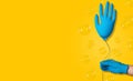 Cleaning concept. A hand in a blue glove holds a ball in the form of a glove on a yellow background. Creative idea. Banner