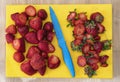 Cleaning, cutting and preparing fresh juicy strawberries with a blue knife in a yellow table Royalty Free Stock Photo