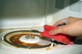 Cleaning a dirty microwave oven. A hand with a sponge and washing foam cleans the microwave from grease and dirt Royalty Free Stock Photo