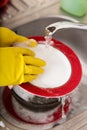 Cleaning dishware kitchen sink sponge washing dish. Close up of female hands in yellow protective rubber gloves washing Royalty Free Stock Photo