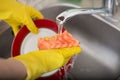 Cleaning dishware kitchen sink sponge washing dish. Close up of female hands in yellow protective rubber gloves washing Royalty Free Stock Photo
