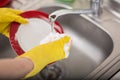 Cleaning dishware kitchen sink sponge washing dish. Close up of female hands in yellow protective rubber gloves washing Royalty Free Stock Photo