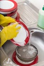 Cleaning dishware kitchen sink sponge washing dish. Close up of female hands in yellow protective rubber gloves washing Royalty Free Stock Photo