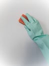 Cleaning and disinfection. A woman in a blue glove holds an orange sponge and washes a light wall Royalty Free Stock Photo