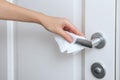 Cleaning door handles with an antiseptic wet wipe and gloves. Woman hand using towel for cleaning home room door link